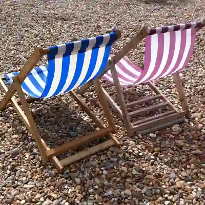 Resorts & Retreats Red striped and blue striped deckchair on Brighton beach.