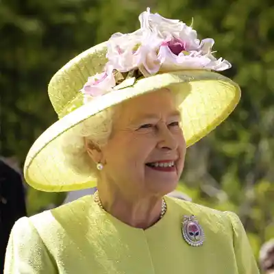 Royalty Queen Elizabeth II in a pale yellow dress and hat.