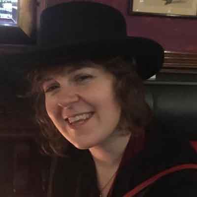 Wearing a hat in the pub smiling.