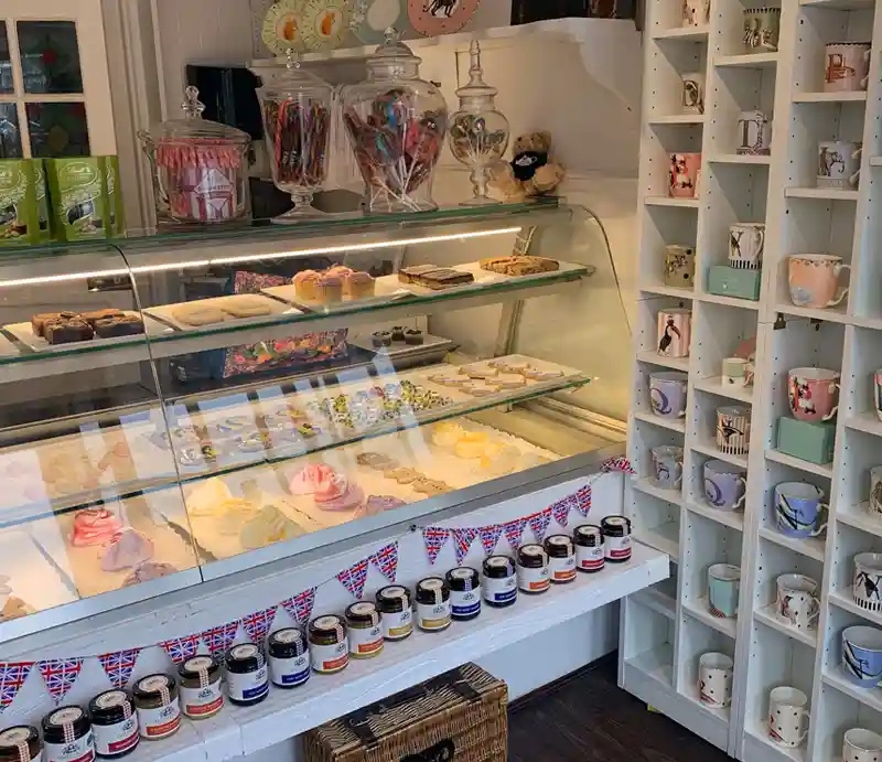 Polly Tea Rooms Interior counter displaying fancy cakes by souvenir mug display.