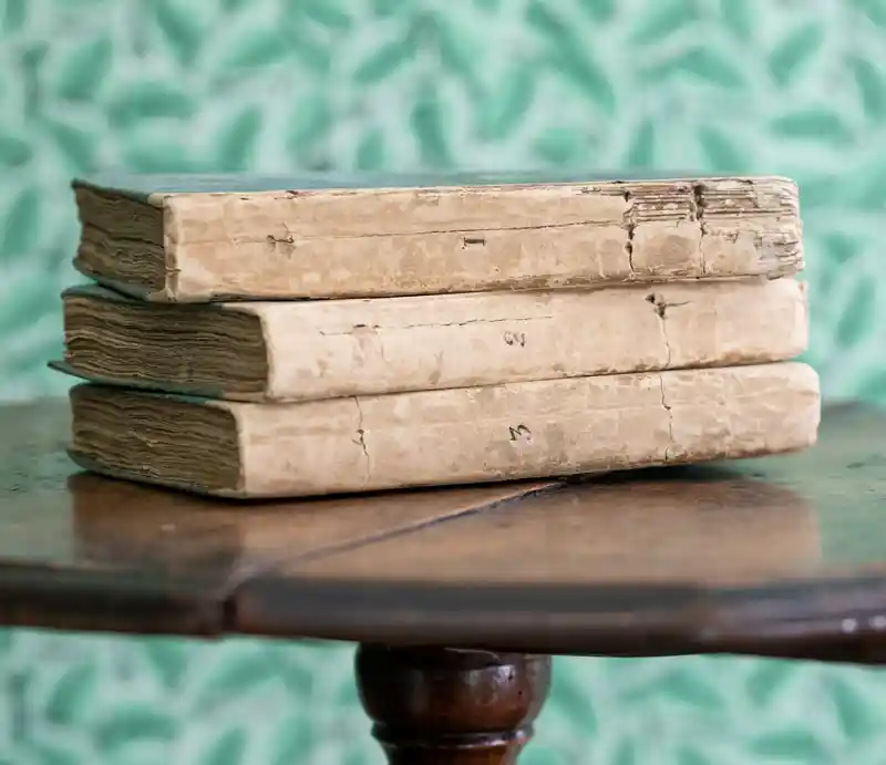 Sense and Sensibility first editions Three numbered books in used condition displayed on a dark wood round table.