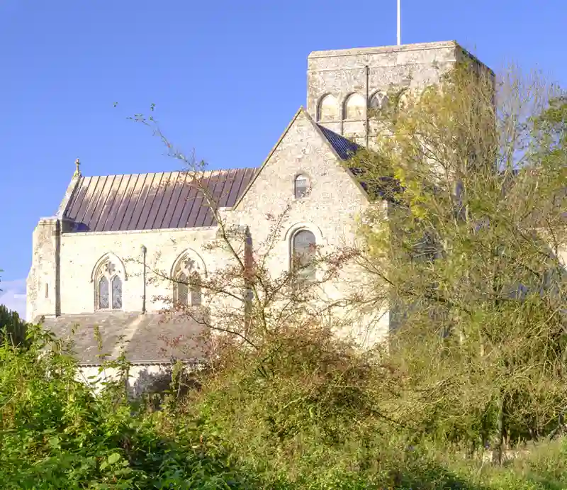 St. Cross Hospital Brick-built medieval building atop a hill surrounded by woodland.