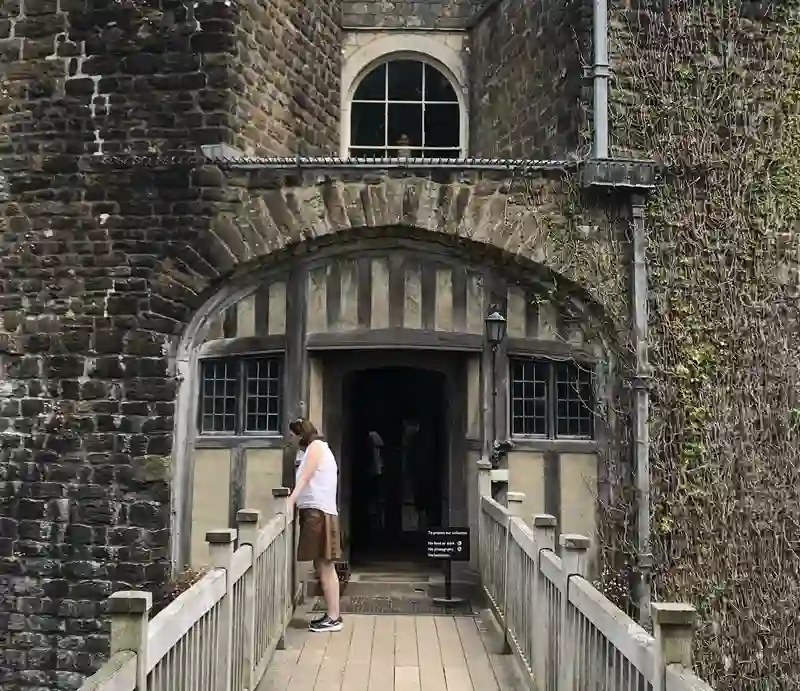 Large, imposing gatehouse made of brick and stone, with wood-built entrance bridge.
