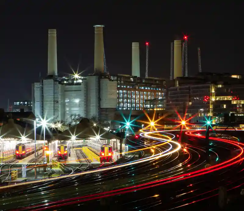 Battersea Power Station Illuminated at night behind the railway tracks.