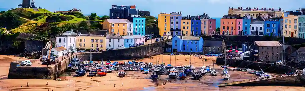 Tenby Colourful painted houses and fishing boats along the seafront.