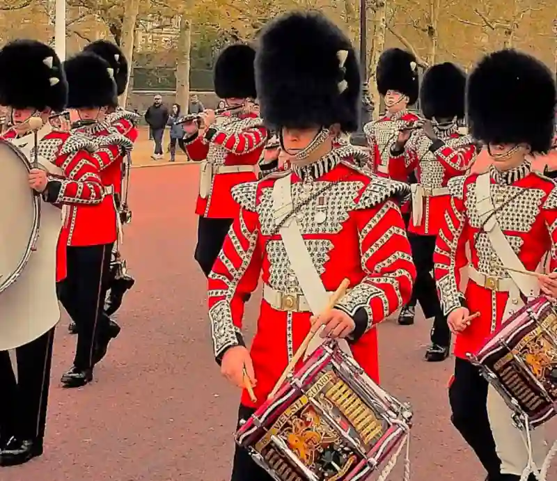 Marching band in red tunics with busby hats.