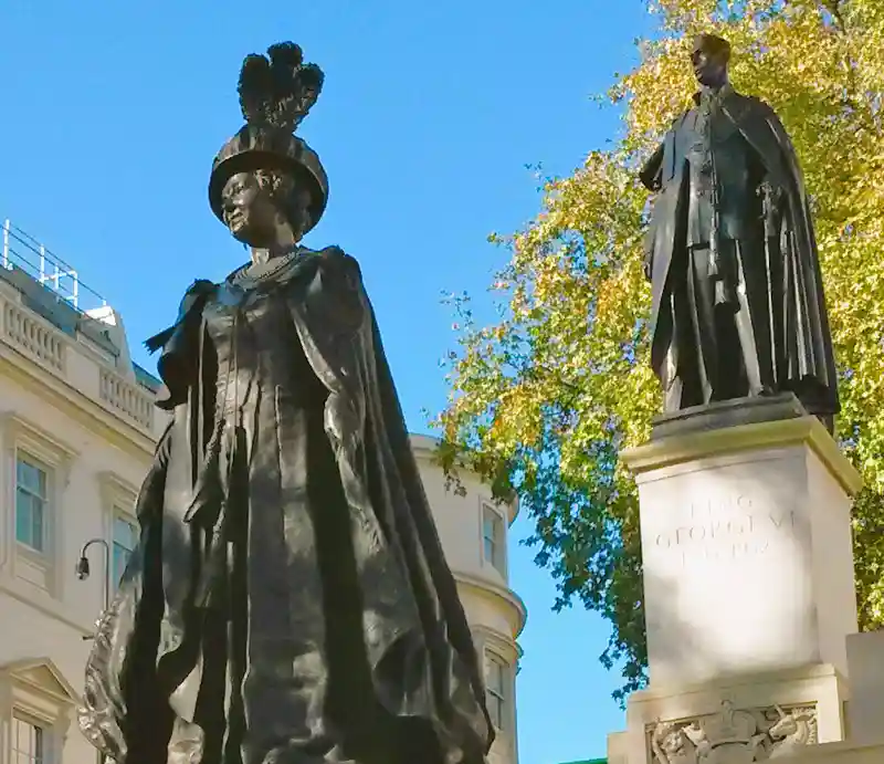 Queen Mother statue Dark bronze in ceremonial robes with George V1 in the background.