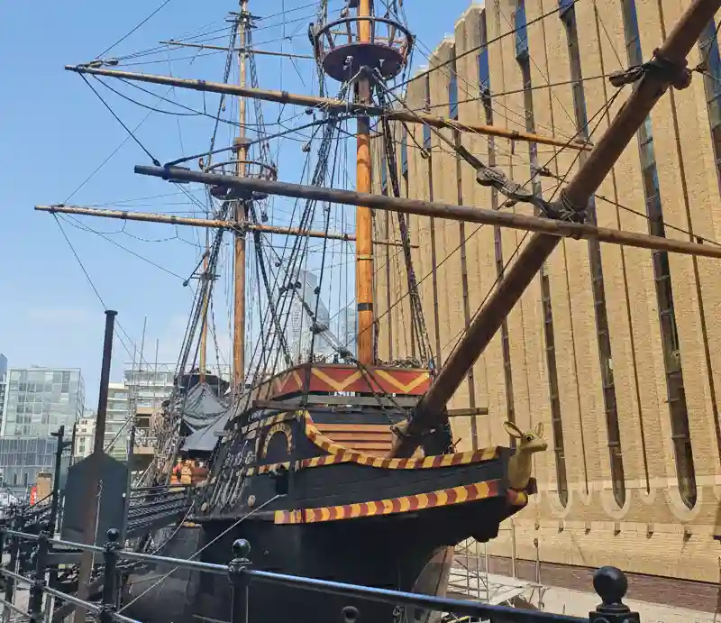 Cutty Sark Black hull decorated with yellow and red trim with tall wooden masts and rigging.