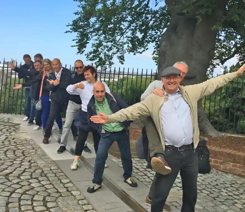 Greenwich Meridian Guests standing astride the line on cobbled surface.