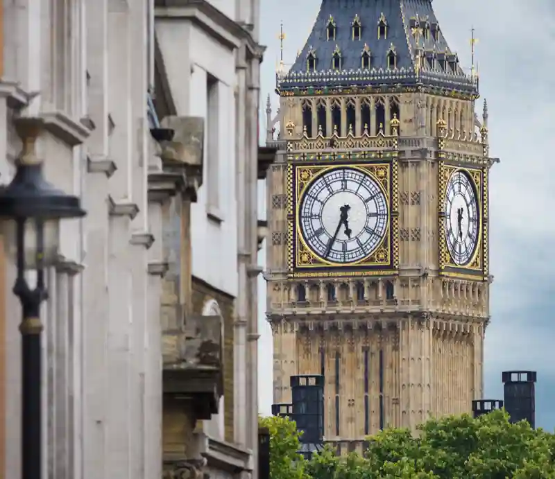 Gothic structure of the clock tower in the distance with classical building to foreground.