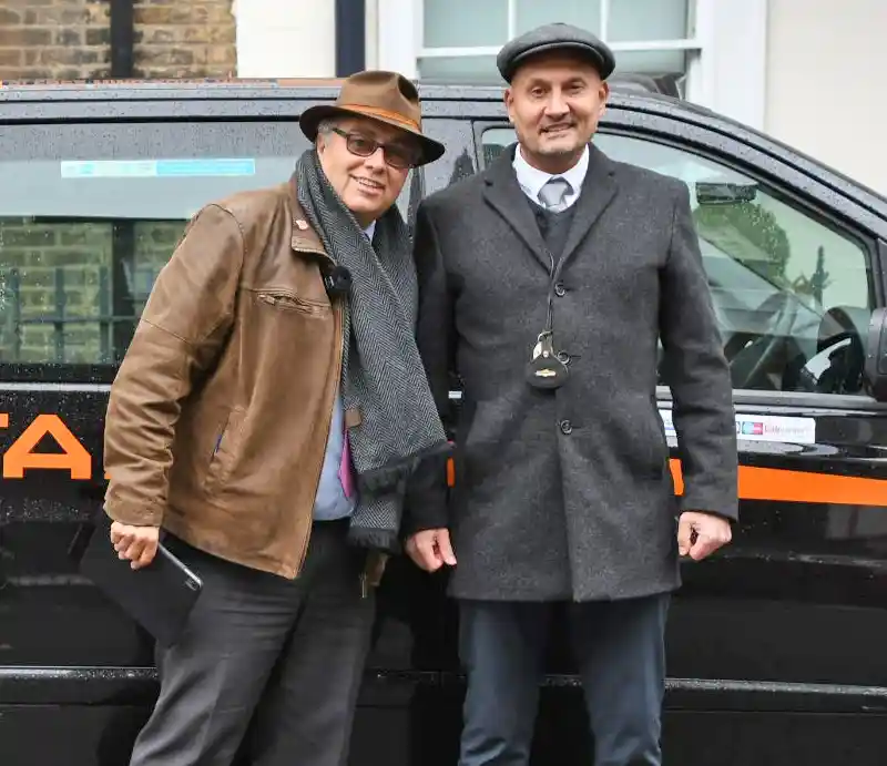 Standing by the taxi.