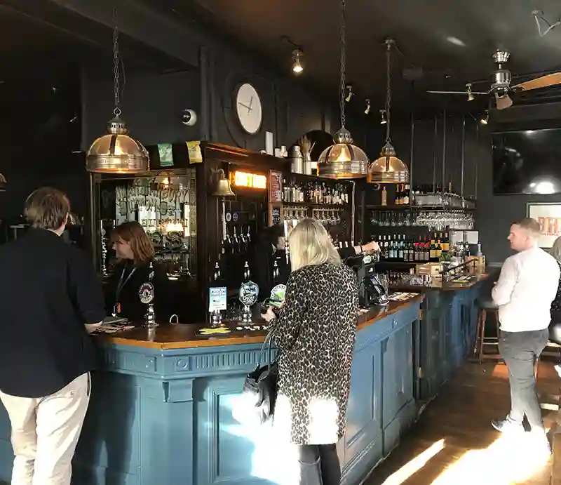Southwark Tavern Blue painted bar with dark decor and customers ordering drinks.