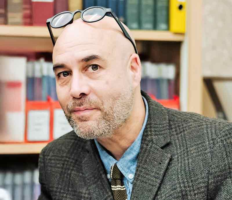 Graham Greenglass tour guide In a library with traditional green tweed jacket.