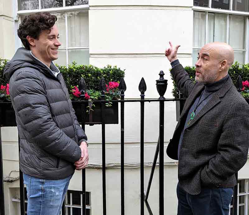 Graham Greenglass with guest Guiding and pointing to a white rendered London building.