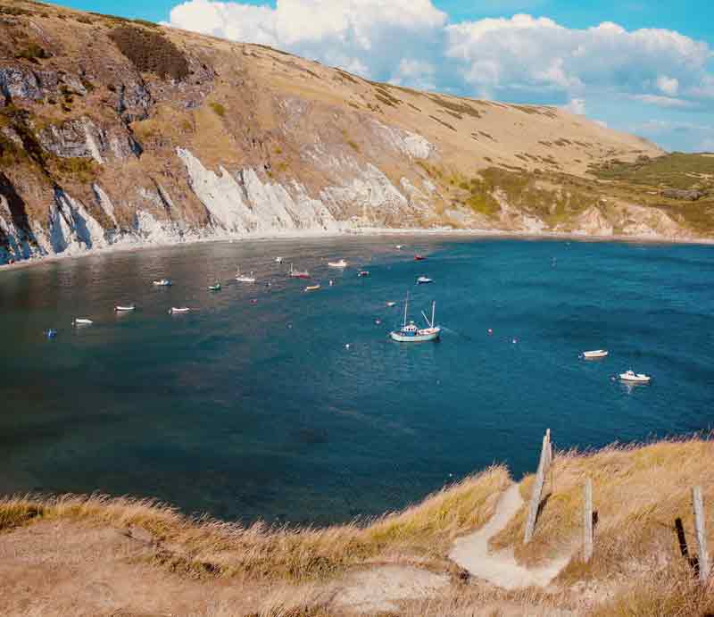 Lulworth Cove Boats below the towering cliffs.