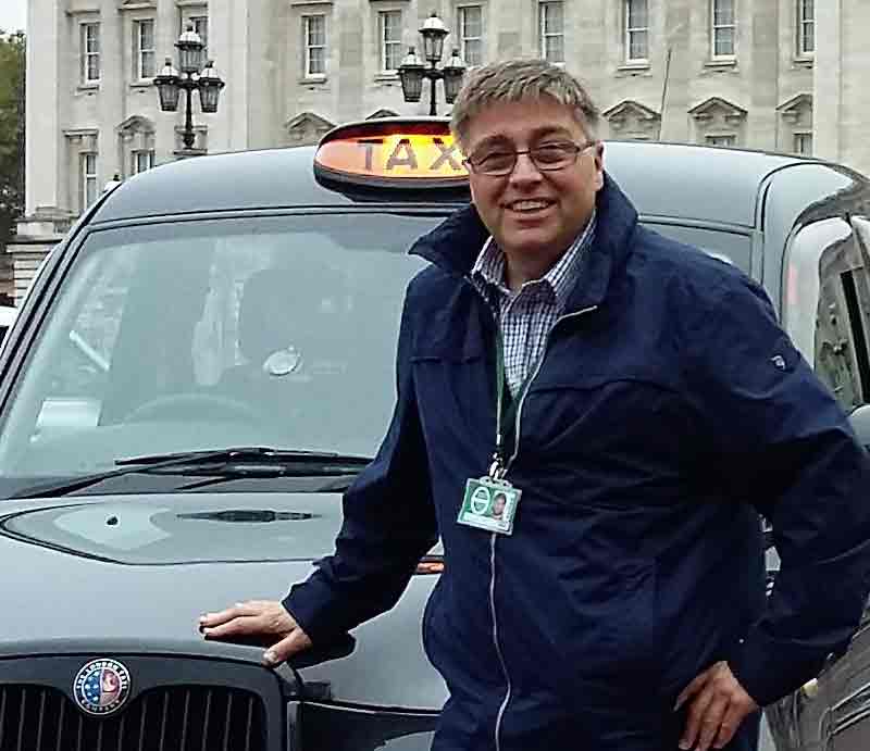 Rob Woodford tour guide Standing by an iconic London Black Cab outside Buckingham Palace..