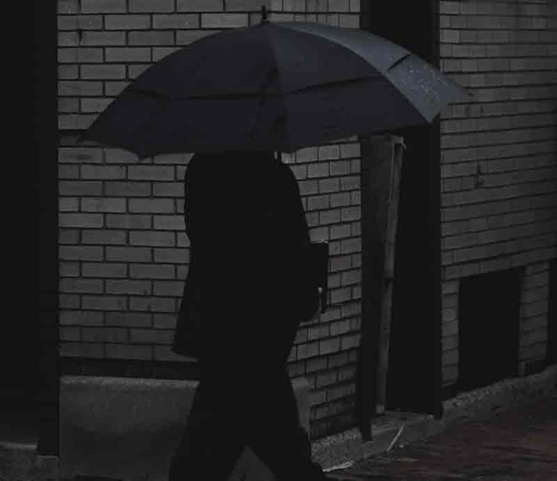 Spy In shadows carrying umbrella.