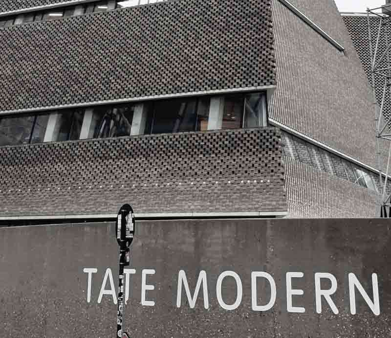 Tate Modern exterior White sign on geometric brick-built structure.