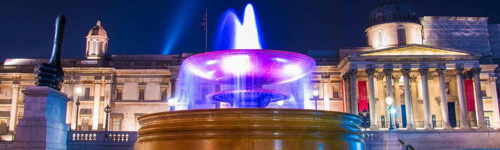 Illuminated in purple at night with National Gallery to background.